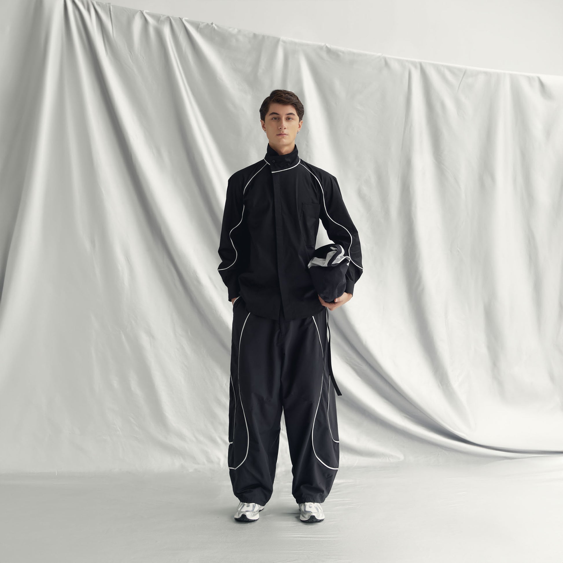 AEREN PANTS | BLACK with wide legs, elastic waistband, drawstring hem, side pockets, and a metallic line design.